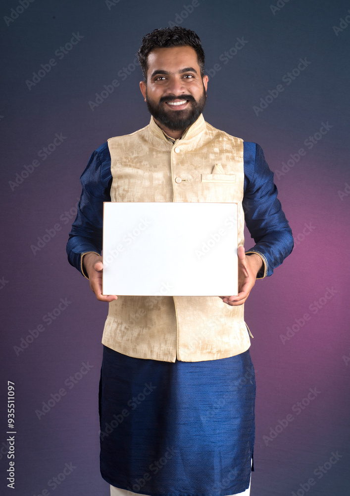 A happy young man is holding and displaying a signboard or placard on a dark background. A happy young man is holding and displaying a signboard or placard on a dark background.