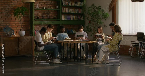 Group of young people of different nationalities are reading the Bible together while sitting at a table indoors. A woman reads aloud