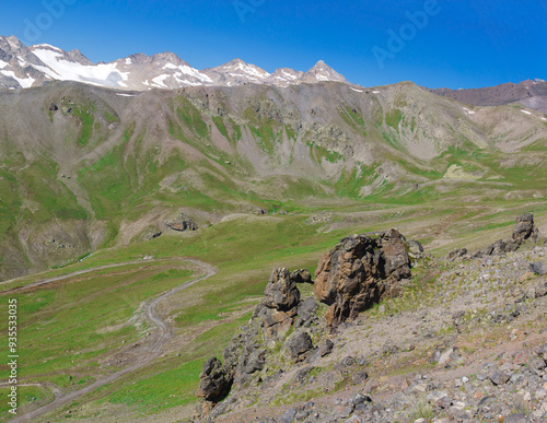 mountain landscape, view of a high mountain valley with alpine meadows from a rocky slope with stone outcrops photo