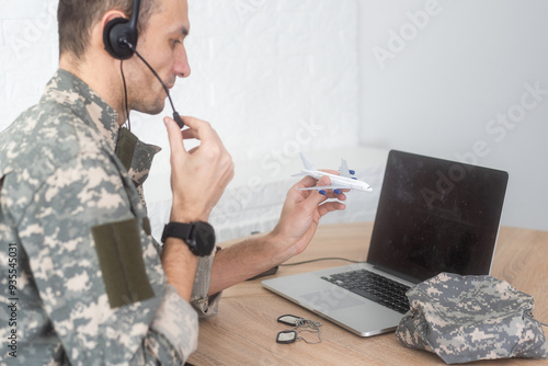 Military Technical Service, Air Force Concept. Hands of a man in uniform holding a silver toy airplane. A middle-aged adult man in a green camouflage uniform. Indoors. 