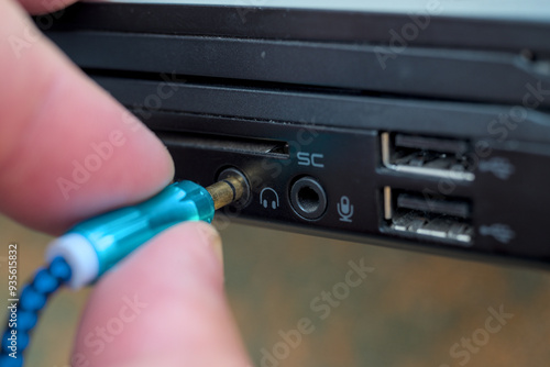 Man connecting headphones 3.5 mm jack in laptop