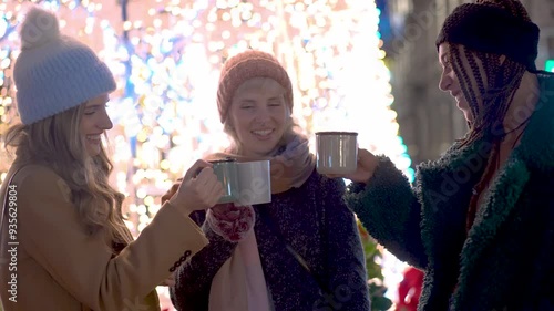 Three friends cheering with hot drinks in christmas market slow motion