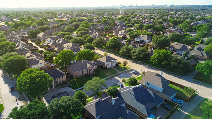 Two story suburban houses in West Plano, Texas with city water tower, downtown buildings skylines background, upscale neighborhood tree lined street in Wentworth Estates, suburbs Dallas, aerial