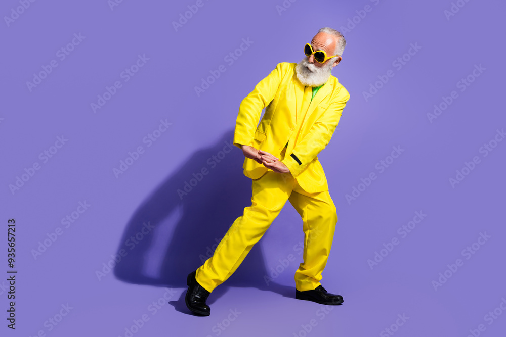 Full body portrait of funny extravagant aged man dance yellow suit isolated on purple color background Full body portrait of funny extravagant aged man dance yellow suit isolated on purple color background