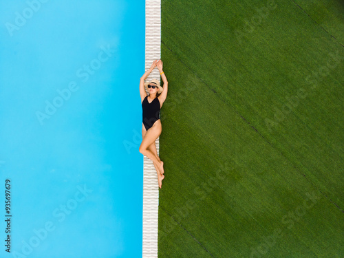 Aerial drone view of woman relaxing near pool in hotel lying on the edge of pool Summer holidays, enjoying summer vacations. Copyspace, space for text