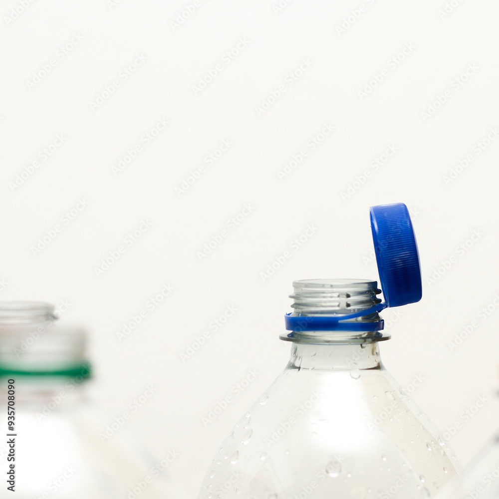 Attached lids on PET bottles on monochrome background Attached lids on PET bottles on monochrome background
