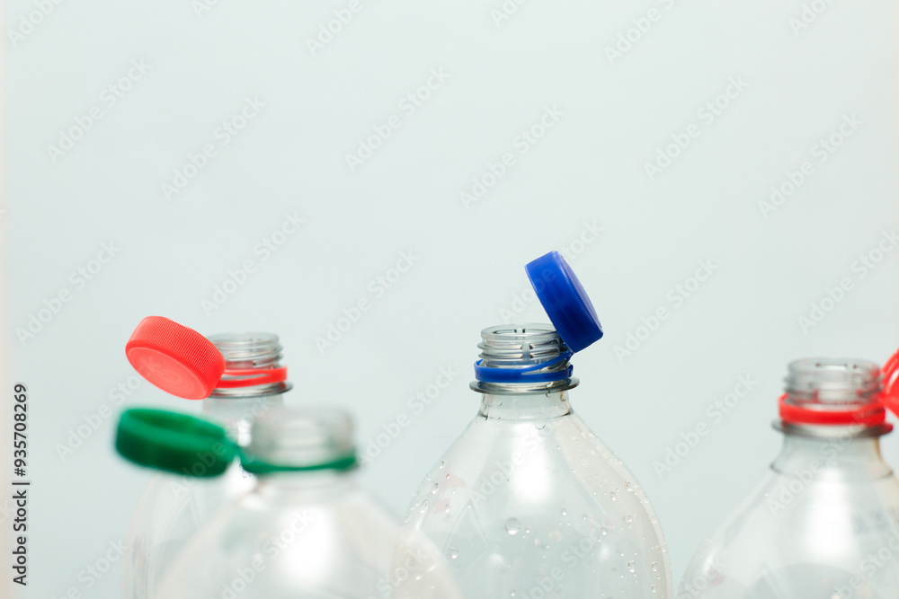 Attached lids on PET bottles on monochrome background Attached lids on PET bottles on monochrome background