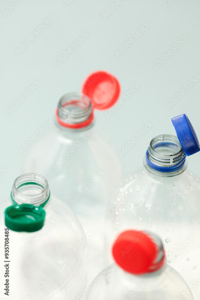 Attached lids on PET bottles on monochrome background Attached lids on PET bottles on monochrome background