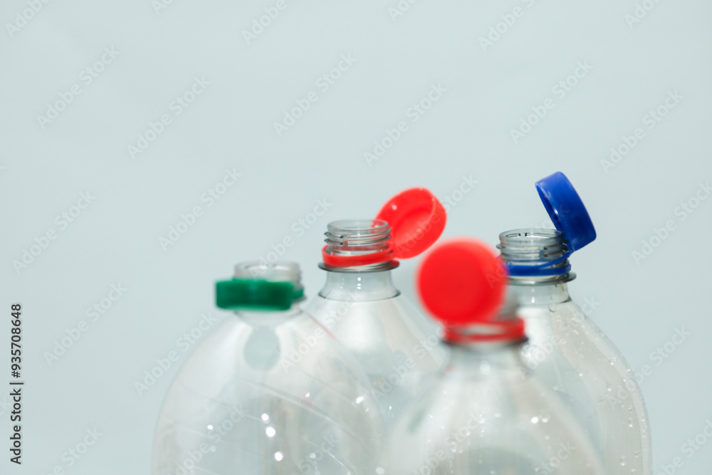 Attached lids on PET bottles on monochrome background Attached lids on PET bottles on monochrome background