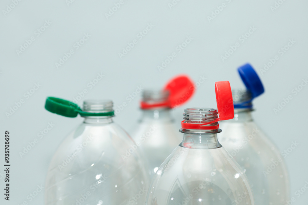 Attached lids on PET bottles on monochrome background Attached lids on PET bottles on monochrome background