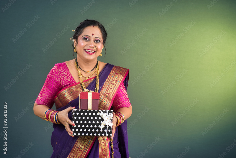 Happy traditional Indian woman wearing saree holding and posing with gift box Happy traditional Indian woman wearing saree holding and posing with gift box