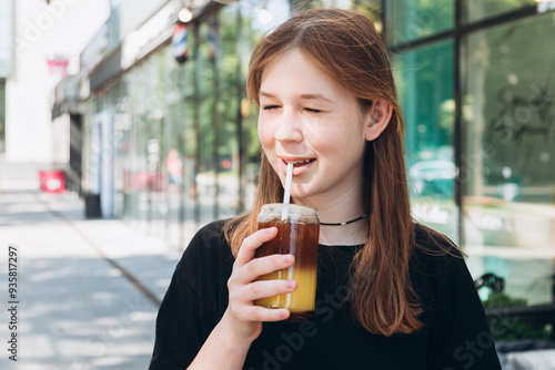 Young girl are drinking a delicious cold coffee with orange juice outdoors.