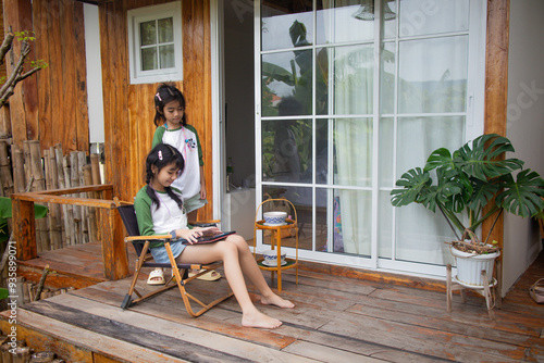 two children are sitting on a porch with a girl reading a book