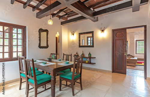 A photograph of an Indian dining room with a wooden table and chairs, white walls, green accents on the furniture. Created with AI