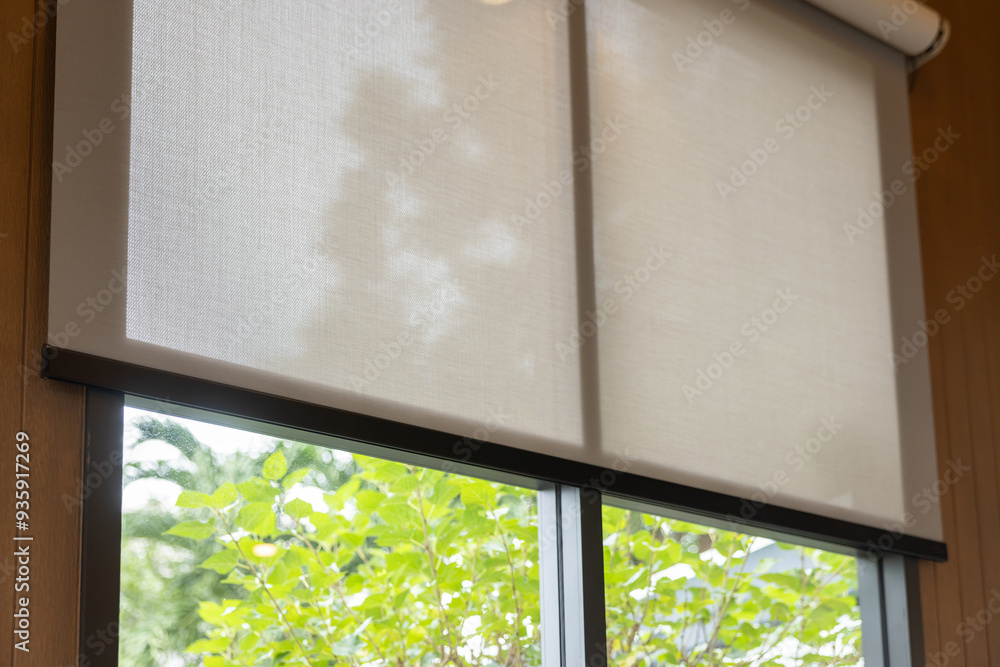 Naklejka premium A window with a white blind and a tree outside