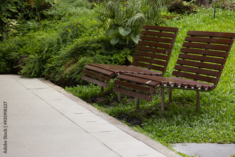 A pair of wooden park benches sit on a grassy hillside A pair of wooden park benches sit on a grassy hillside