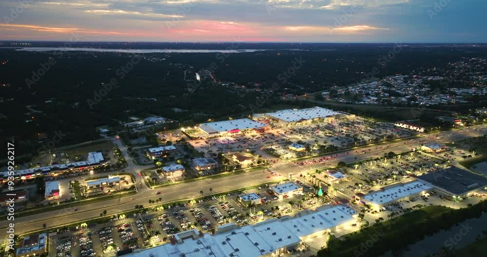 Shopping plaza stores and malls at night and American wide highway with many driving cars in North Port, Florida. USA retail and transportation infrastructure. Shopping plaza stores and malls at night and American wide highway with many driving cars in North Port, Florida. USA retail and transportation infrastructure.