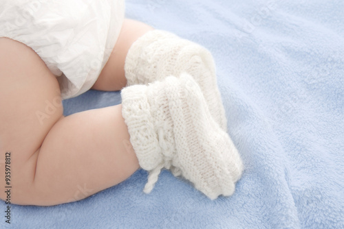 baby feet in warm woolen white stockings on a blue blanket 