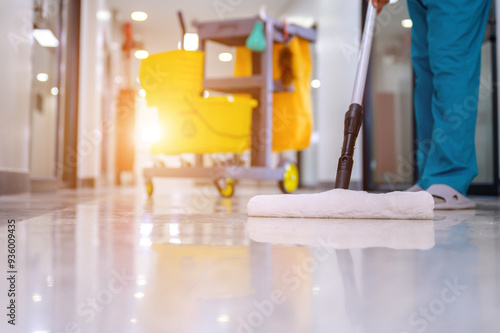 A close-up of mop mopping floor cleaning in office with cleaning cart and floor cleaning tools and equipment using mop cleaning from epoxy floor