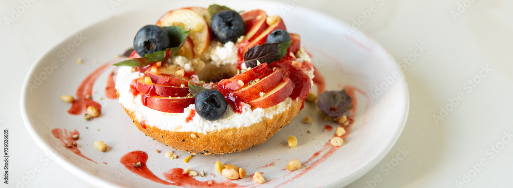 bagel with cream cheese, peaches and blueberries on a white plate on a light table bagel with cream cheese, peaches and blueberries on a white plate on a light table