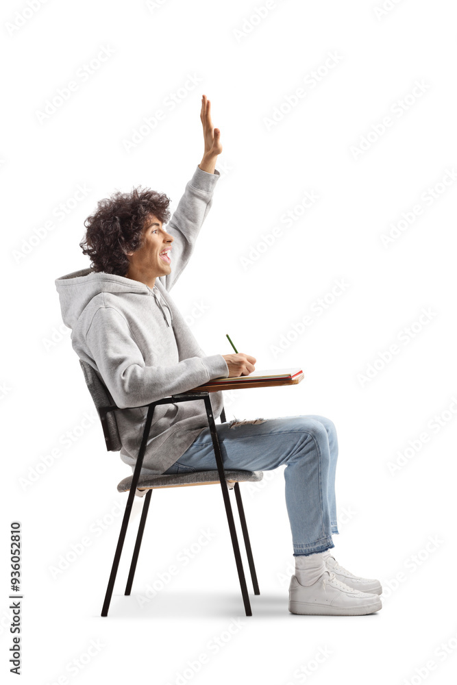 Male student sitting in a school chair and raising hand Male student sitting in a school chair and raising hand