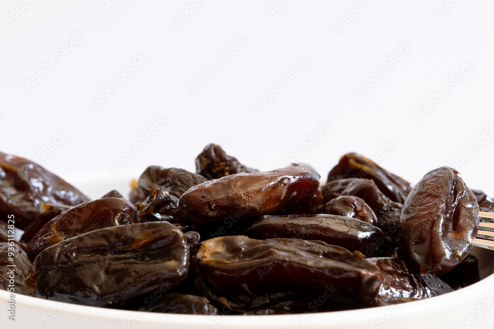 Portion of dried dates inside a ceramic bowl photographed close up Portion of dried dates inside a ceramic bowl photographed close up