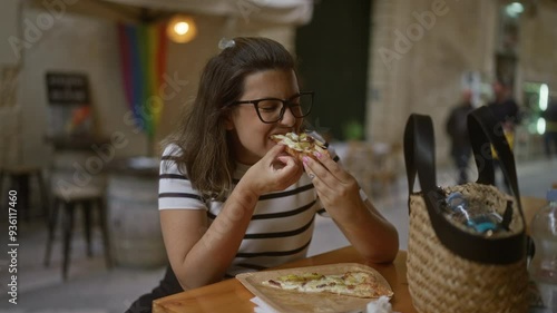 A young woman enjoying pizza on an outdoor restaurant terrace in italy.