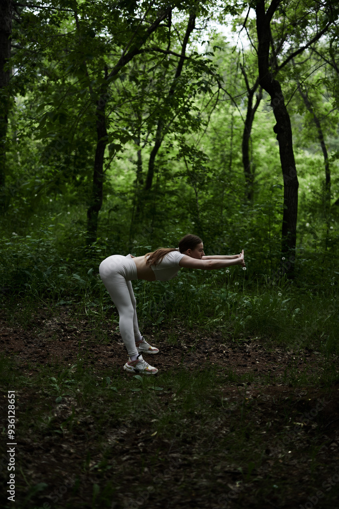 Young caucasian woman in white sportswear exercising in green forest park Young caucasian woman in white sportswear exercising in green forest park