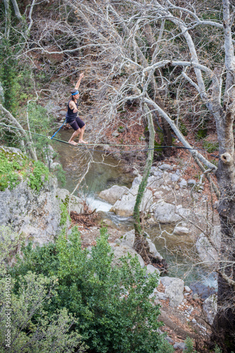 A tightrope walker walks along a cable stretched over a canyon.