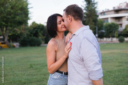 A happy smiling couple walking, hugging and kissing in park on late summer sunset photo