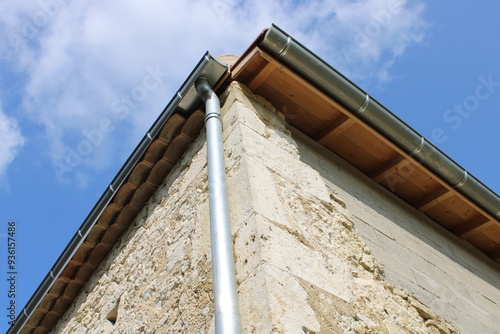 Gouttière zinc gris sur la façade de la maison, descentes rondes et sous-face en lambris bois photo