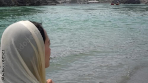 A girl in a blue dress walks on the beach near the Ganges. Rishikesh, India.