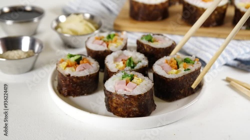 Traditional Korean food kimbap, with ham, vegetables and lettuce. Cooking process, making homemade kimbap, step by step cooking and cutting slicing with hands in pic, top view