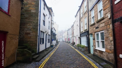 People walking along the quite streets of Staithes a sleepy fishing village on the Yorkshire coast of England. With cobbled streets and old stone built houses. Harbor walls and friendly public houses.