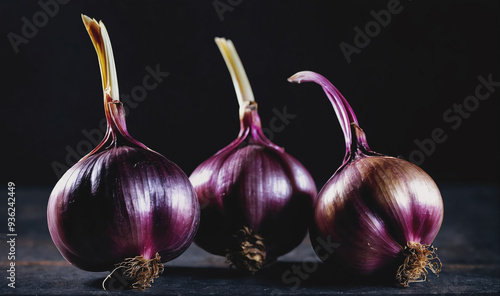 Three purple onions sit on a black surface photo