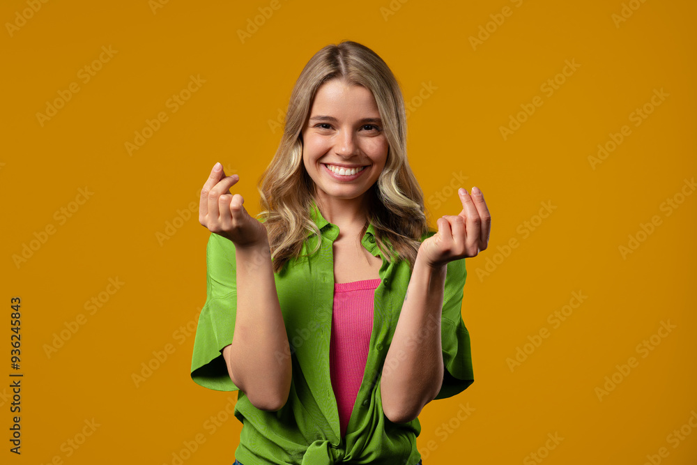Young woman with money gesture on yellow studio background. Smart lady smiling Young woman with money gesture on yellow studio background. Smart lady smiling