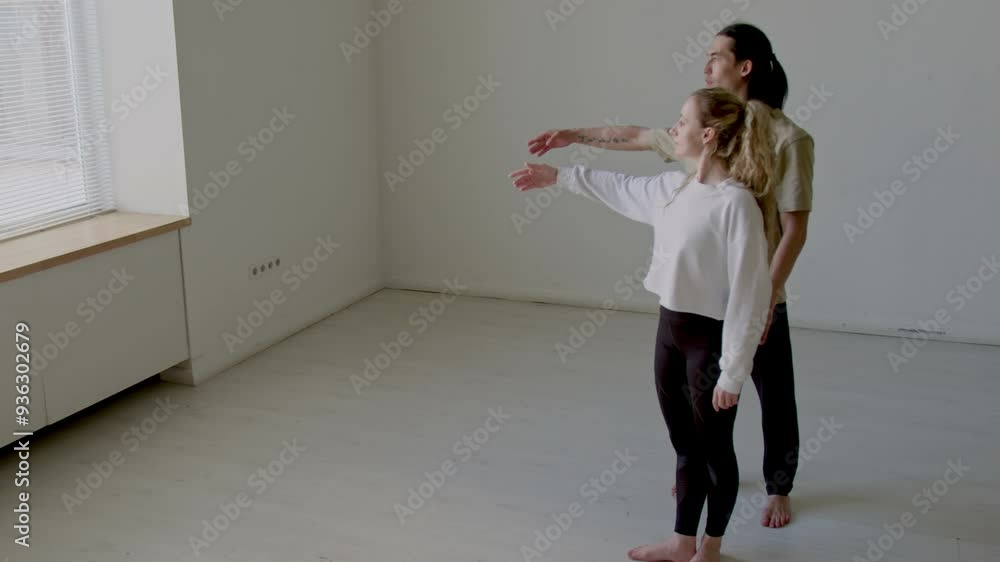 Young woman learning third ballet position with help of male dance teacher during lesson in studio Young woman learning third ballet position with help of male dance teacher during lesson in studio