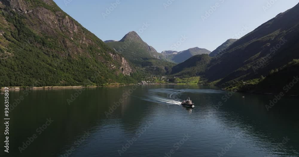 Ferry Boat Cruises with Passengers through Norwegian Fjord. Geiranger in Background Ferry Boat Cruises with Passengers through Norwegian Fjord. Geiranger in Background