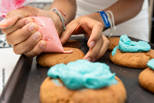 Girl using piping bag to frost cookies with blue and pink icing photo