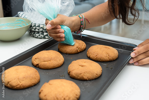 Girl decorating freshly baked cookies with a piping bag. photo