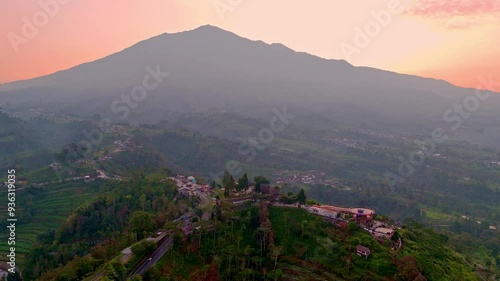 Aerial view of beautiful rural landscape of highland in sunrise time with mountain background. Indonesian rural mountain landscape. Ketep Pass and Merbabu Mountain. 4k drone shot. photo