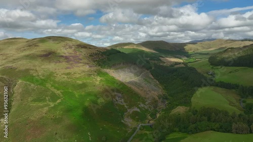 Altitude panning view of forested mountain pass and craggy green mountains under cloudy summer sky. Whinlatter Pass, Lake District National Park, Cumbria, UK photo