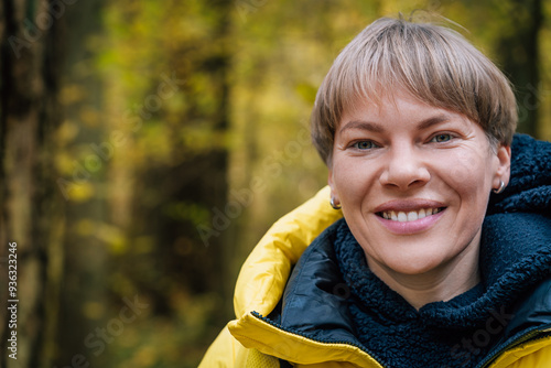 Smiling blonde woman enjoying autumn forest walk photo