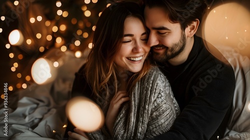 Handsome young family hugge photo portrait with electric lights on background. Enamored couple on winter vacation. Happy man cuddling woman from behind. Youth people in warm wool clothes