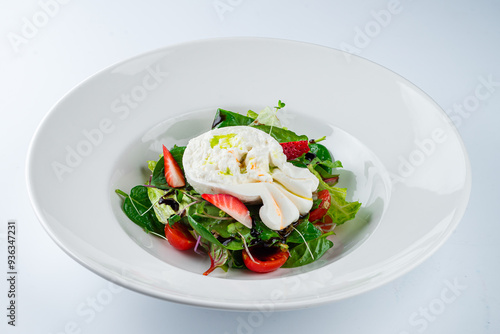 Green salad with burata cheese, strawberries, cherry tomatoes, spinach, beet leaves, lettuce and balsamic sauce in a plate.