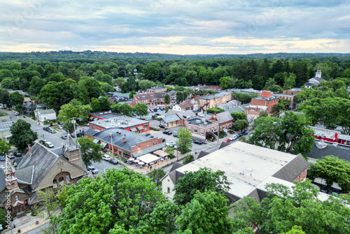 aerial view of rhinebeck new york (hudson valley small town next to catskill mountains) trees main street homes businesses houses (residential and commercial downtown area) drone looking down sunset