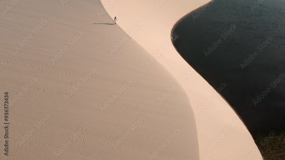 Pessoa andando nas dunas no por do sol com imagem de drone