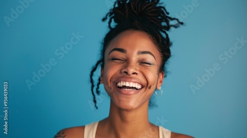 A radiant African American woman with lovely locks beams with joy, capturing the essence of happiness against a striking blue background, radiating positivity