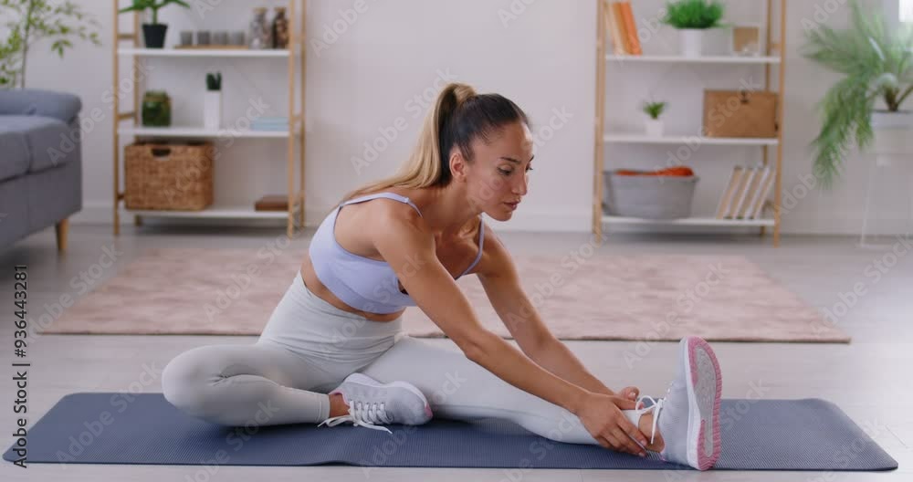 Young sporty woman doing stretching exercises sitting on yoga mat at home. Athletic girl exercising indoors. Healthy lifestyle, fitness and sport concept. 4k video. Slow motion video. Young sporty woman doing stretching exercises sitting on yoga mat at home. Athletic girl exercising indoors. Healthy lifestyle, fitness and sport concept. 4k video. Slow motion video.