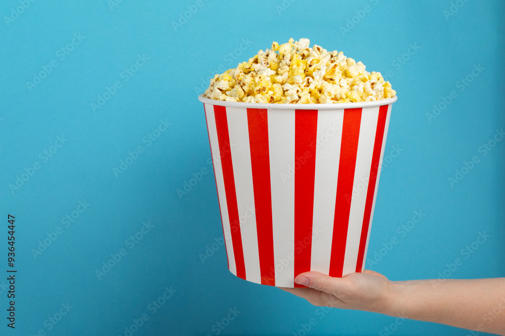 Popcorn box. Red and white striped buckets of salted popcorn on a colored background. Cinema and entertainment concept. Movie night with popcorn. Delicious appetizer, snack. Place for text. Popcorn box. Red and white striped buckets of salted popcorn on a colored background. Cinema and entertainment concept. Movie night with popcorn. Delicious appetizer, snack. Place for text.